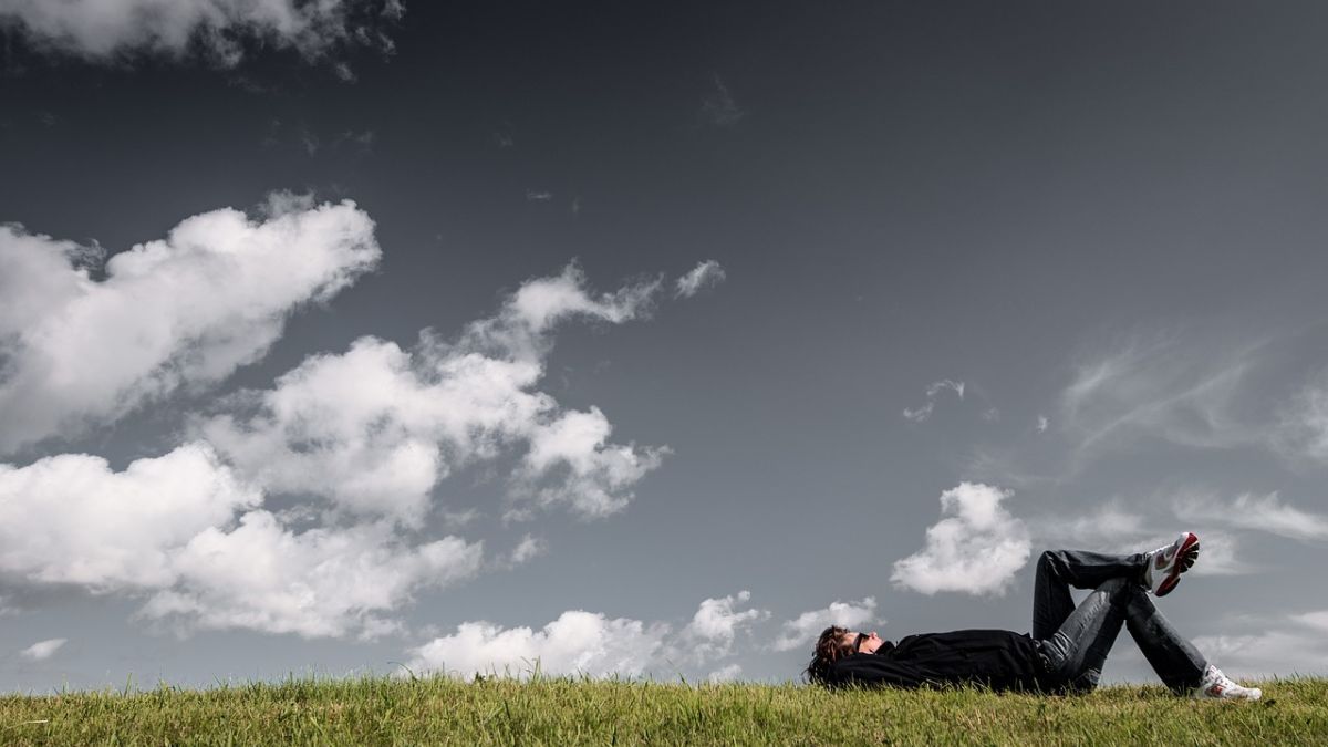 草原に寝転がって空を見上げる人